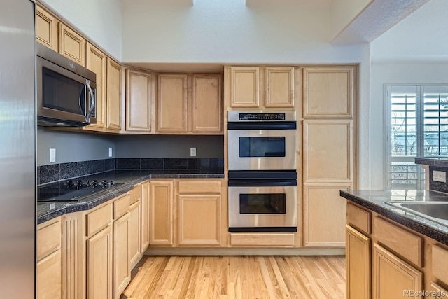 kitchen with light hardwood / wood-style floors, light brown cabinetry, and appliances with stainless steel finishes