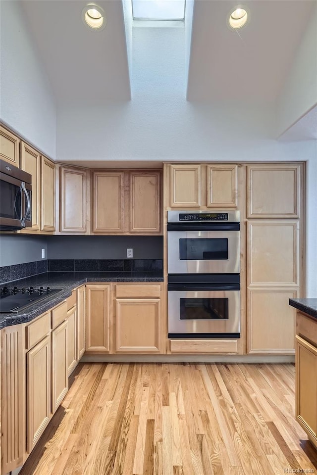 kitchen with light hardwood / wood-style floors, light brown cabinets, and appliances with stainless steel finishes