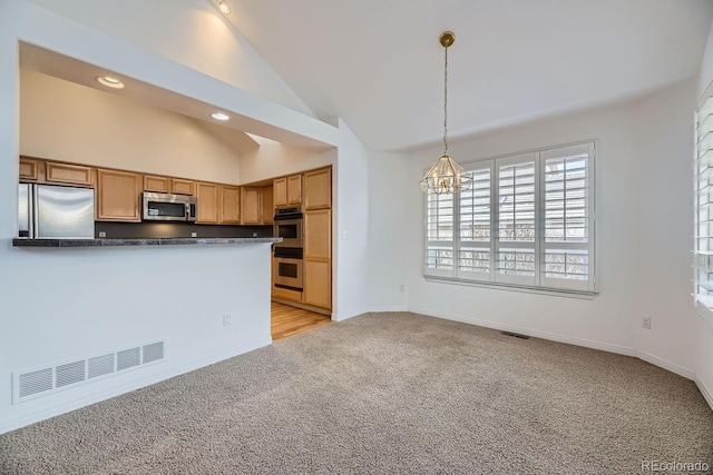 kitchen featuring a notable chandelier, appliances with stainless steel finishes, hanging light fixtures, light carpet, and kitchen peninsula