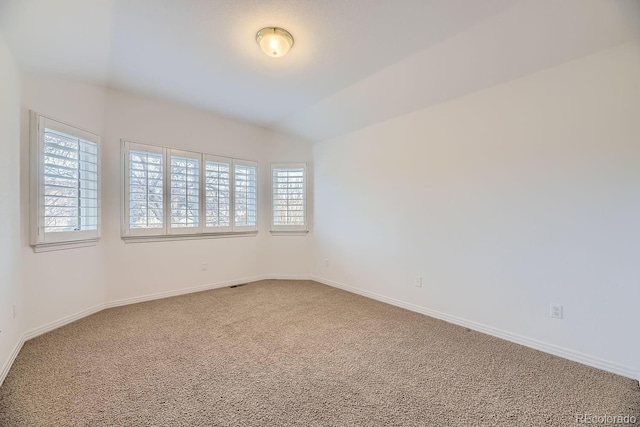 carpeted empty room with vaulted ceiling