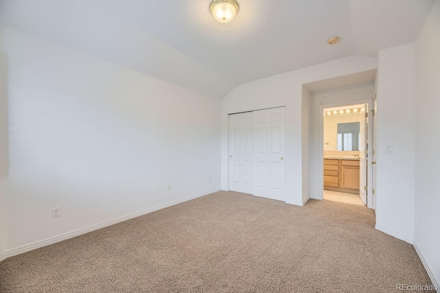 unfurnished bedroom with light carpet, a closet, and vaulted ceiling