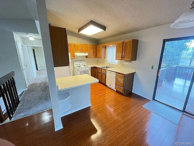 kitchen with lofted ceiling, sink, white appliances, hardwood / wood-style floors, and a textured ceiling