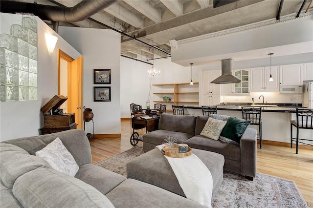 living room with light wood finished floors, a chandelier, and baseboards