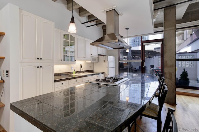 kitchen featuring white appliances, island exhaust hood, tile counters, glass insert cabinets, and white cabinets