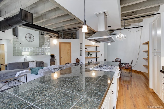 kitchen featuring tile counters, island range hood, white cabinets, and hanging light fixtures