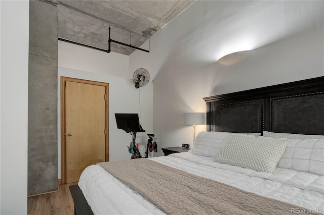 bedroom featuring wood finished floors and a towering ceiling