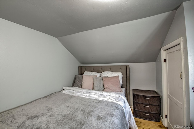 bedroom featuring light wood-type flooring and lofted ceiling