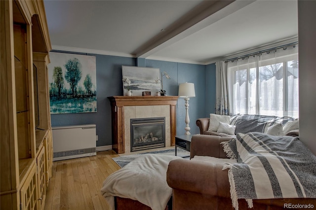 living area featuring baseboards, a fireplace, crown molding, radiator, and light wood finished floors