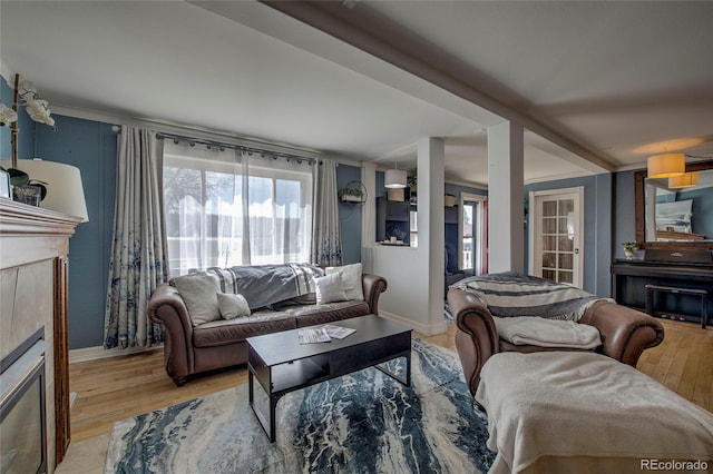 living room featuring a glass covered fireplace, light wood finished floors, and baseboards