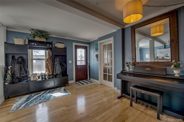foyer entrance with baseboards, crown molding, and wood finished floors