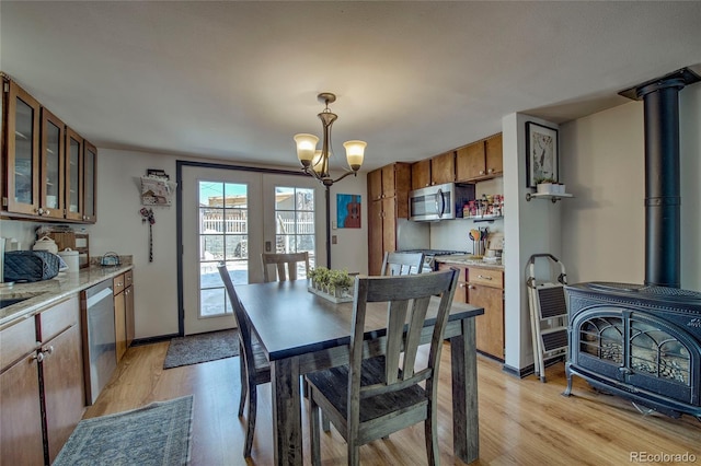 dining area with a chandelier, a wood stove, light wood-style floors, and baseboards