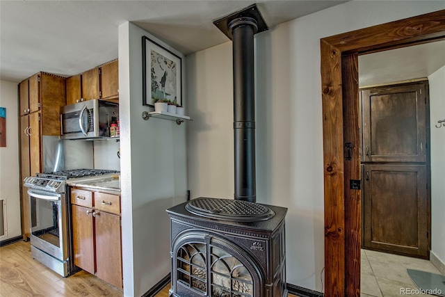 306 Elm St, Leadville, CO 80461 - kitchen with appliances with stainless steel finishes, a wood stove, light countertops, light wood-style flooring, and brown cabinetry