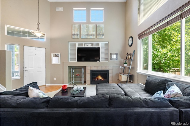 10262 Spotted Owl Ave, Highlands Ranch, CO 80129 - living area featuring a towering ceiling, a tiled fireplace, and wood finished floors