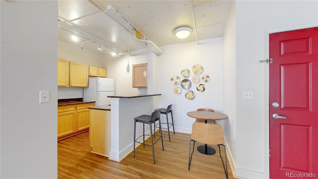 444 17th St Unit 301, Denver, CO 80202 - kitchen with freestanding refrigerator, dark countertops, a kitchen breakfast bar, and light wood-style floors