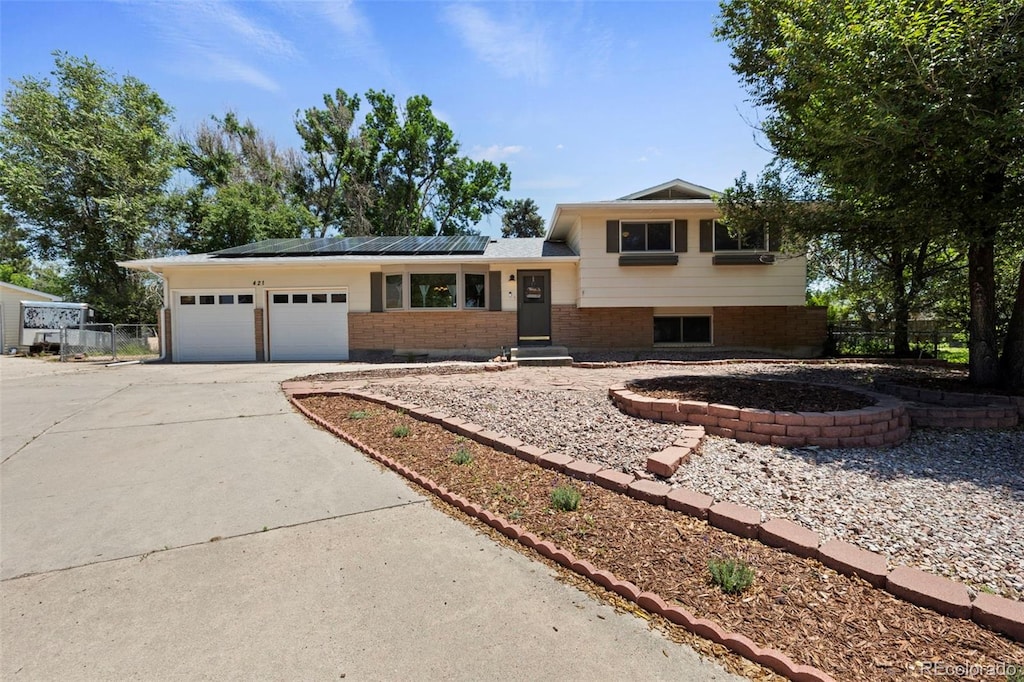 421 Harvard St, Colorado Springs, CO 80911 - split level home featuring driveway, roof mounted solar panels, an attached garage, and brick siding