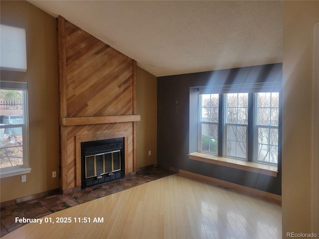 unfurnished living room with a fireplace, a wealth of natural light, hardwood / wood-style floors, and a textured ceiling