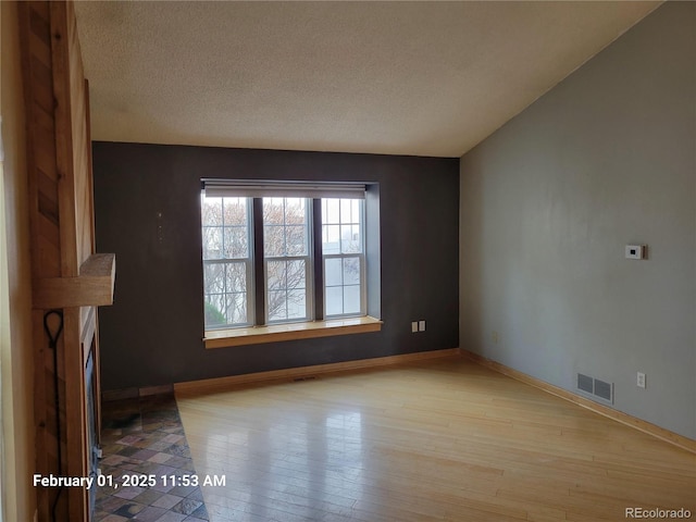 unfurnished living room with light hardwood / wood-style flooring and a textured ceiling