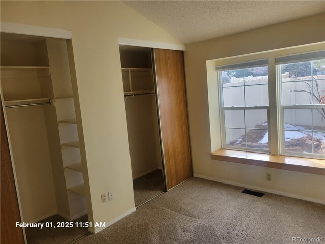 unfurnished bedroom with vaulted ceiling, carpet floors, and a textured ceiling