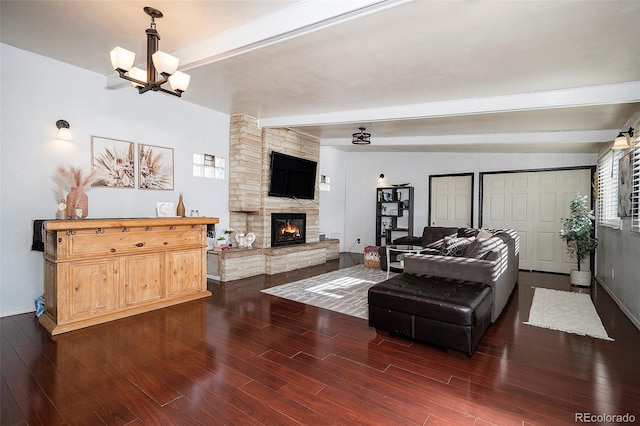 living room with vaulted ceiling with beams, a stone fireplace, dark wood-type flooring, and an inviting chandelier