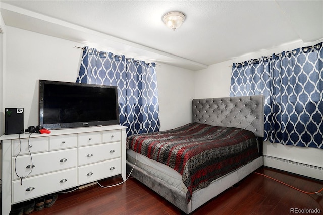 bedroom with dark wood-type flooring and a baseboard heating unit