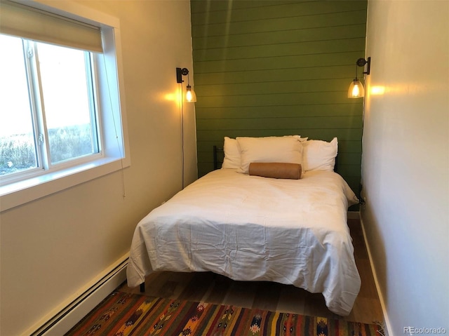 bedroom featuring hardwood / wood-style flooring and a baseboard heating unit