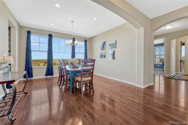 dining room with arched walkways, recessed lighting, wood finished floors, a chandelier, and baseboards