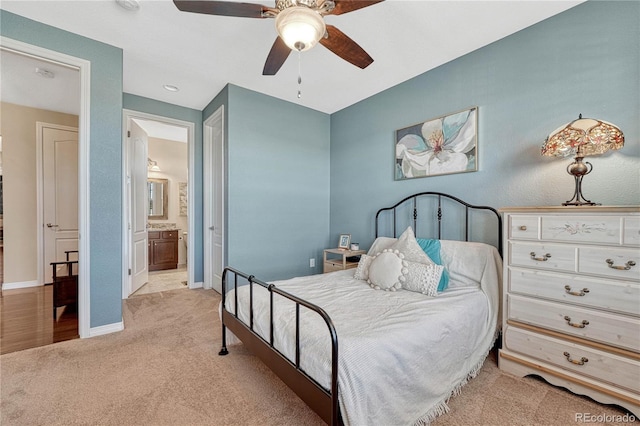 bedroom with baseboards, ensuite bathroom, a ceiling fan, and light colored carpet