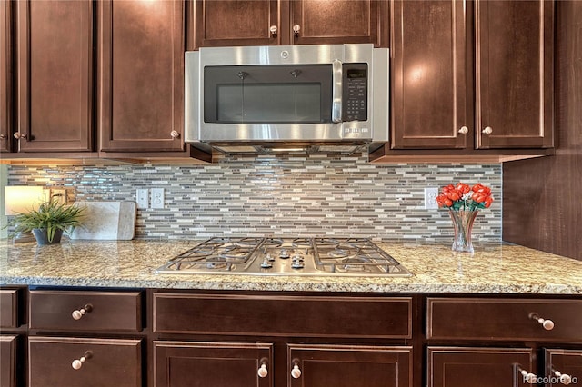 kitchen with appliances with stainless steel finishes, backsplash, and dark brown cabinets