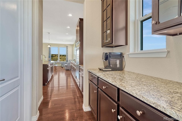 kitchen with open floor plan, glass insert cabinets, dark wood finished floors, and dark brown cabinetry