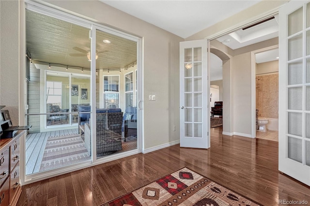 doorway featuring arched walkways, french doors, wood finished floors, and baseboards