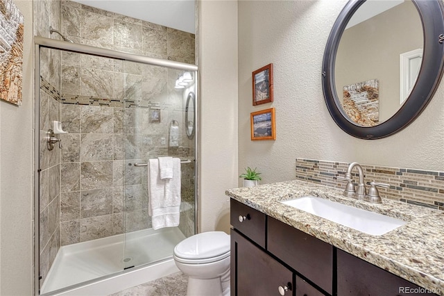 full bathroom with tasteful backsplash, a textured wall, toilet, vanity, and a shower stall