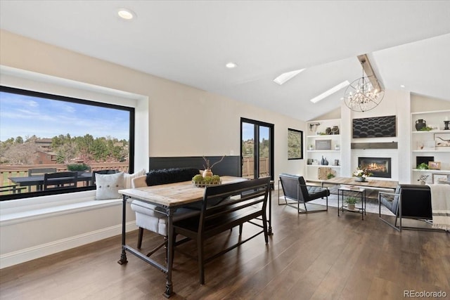 dining space featuring an inviting chandelier, a glass covered fireplace, built in shelves, lofted ceiling with beams, and dark wood finished floors