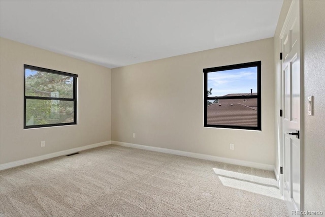 carpeted empty room with plenty of natural light, baseboards, and visible vents