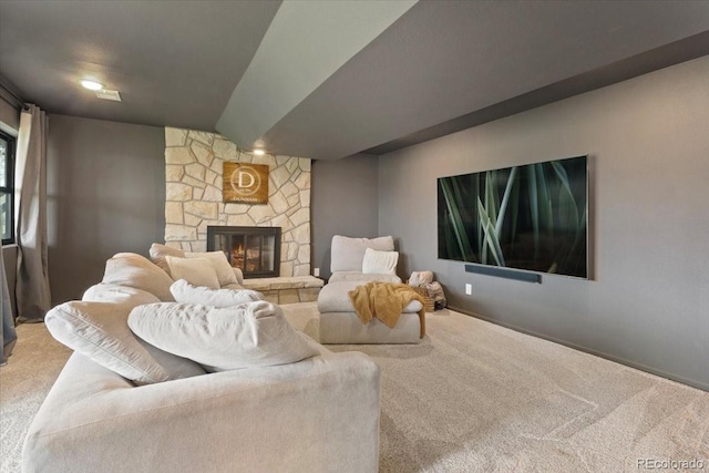 carpeted living area featuring baseboards and a stone fireplace
