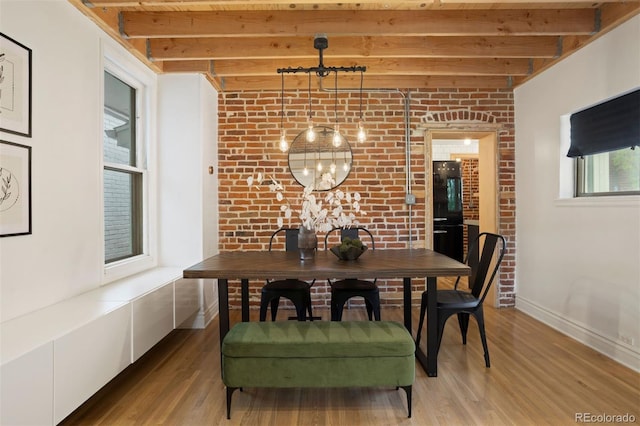 dining space with light wood-type flooring, beam ceiling, baseboards, and brick wall