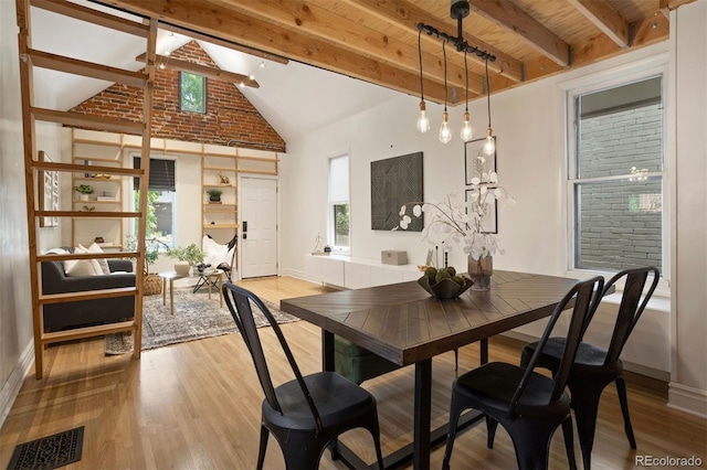 dining room with high vaulted ceiling, visible vents, beam ceiling, and wood finished floors