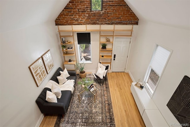 living area featuring vaulted ceiling, wood finished floors, and baseboards