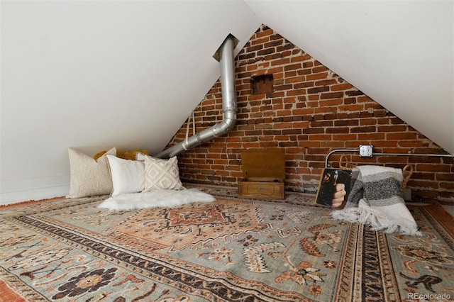 bedroom with lofted ceiling and brick wall