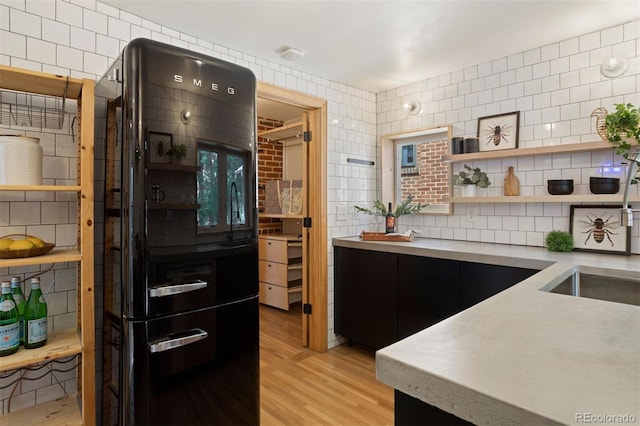 kitchen with tile walls, light wood-style floors, light countertops, backsplash, and freestanding refrigerator