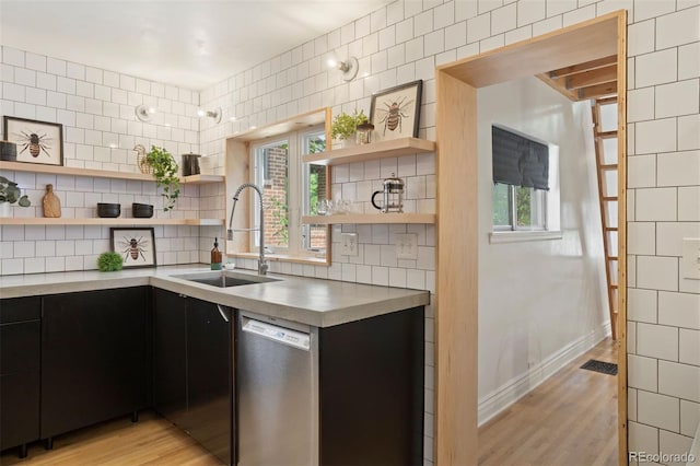 kitchen with open shelves, stainless steel dishwasher, a sink, and dark cabinetry