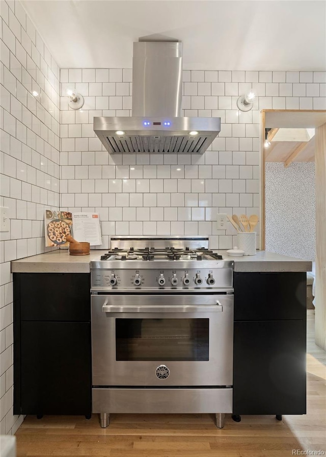 kitchen with light countertops, light wood-type flooring, high end stainless steel range oven, decorative backsplash, and island exhaust hood