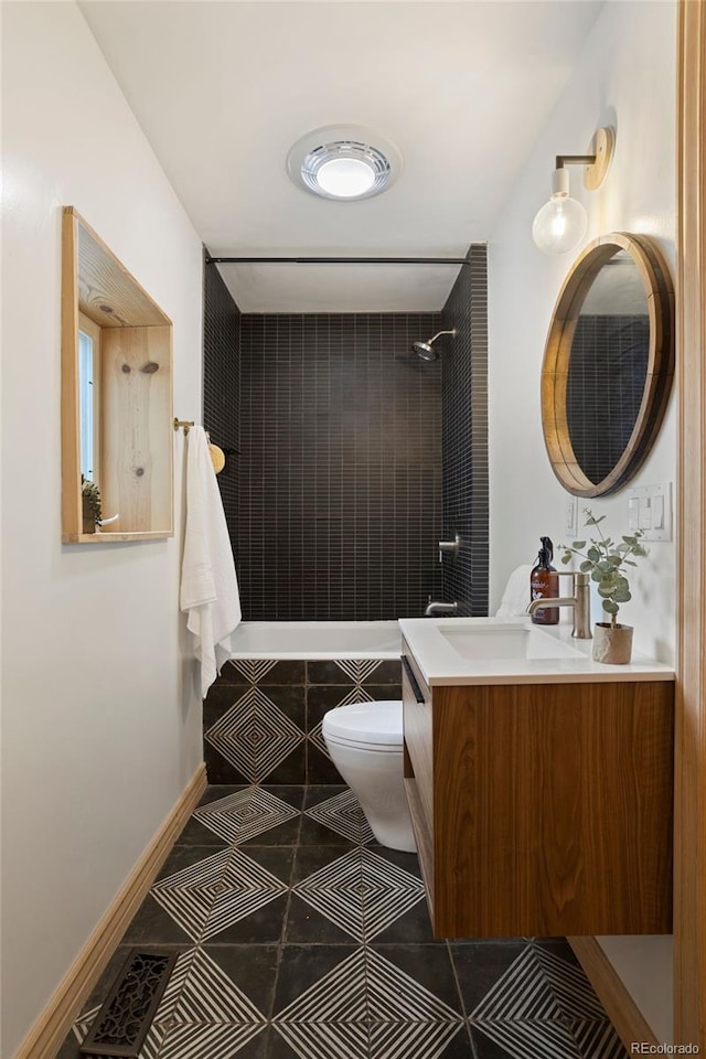 bathroom with baseboards, toilet, tile patterned flooring, a tile shower, and vanity