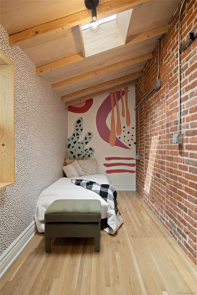 bedroom featuring brick wall, beamed ceiling, wood finished floors, and baseboards