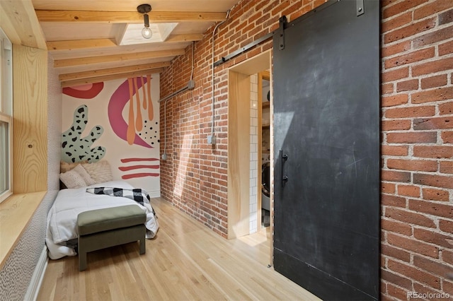 hall featuring brick wall, a barn door, wood finished floors, and beam ceiling