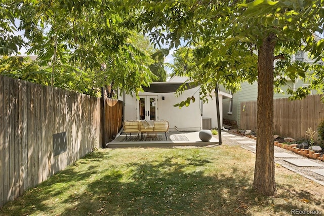 view of yard with a patio area, french doors, a fenced backyard, and central air condition unit