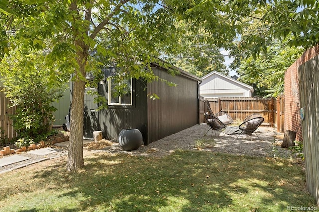 view of side of home with a yard, a fenced backyard, a shed, and an outdoor structure