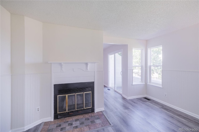 unfurnished living room with light wood-type flooring and a textured ceiling