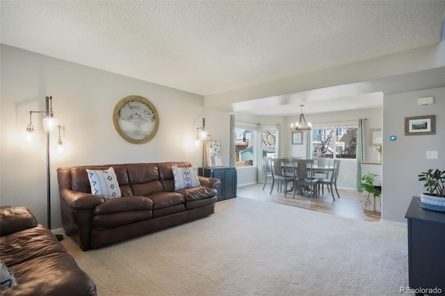 living area with light colored carpet, baseboards, a notable chandelier, and a textured ceiling