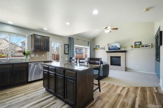 kitchen with a breakfast bar area, lofted ceiling, ceiling fan, a sink, and stainless steel dishwasher