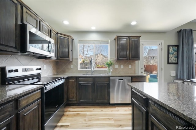 kitchen featuring a sink, stainless steel appliances, plenty of natural light, and light wood-style flooring